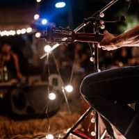 A musician wearing a plaid shirt is playing guitar on stage.Concert,mini concert and music festivals.